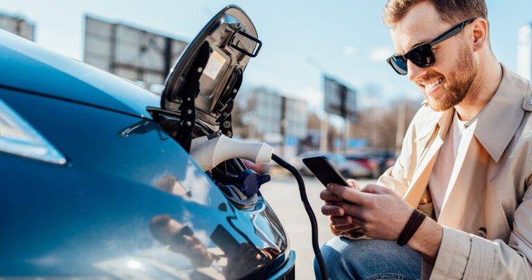 person-crouched-next-to-charging-ev